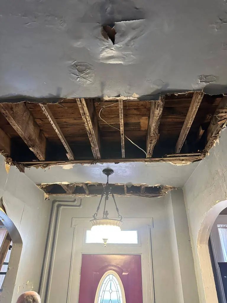 Entry hall ceiling collapsed and joists exposed after a burst radiator pipe sent water through the house