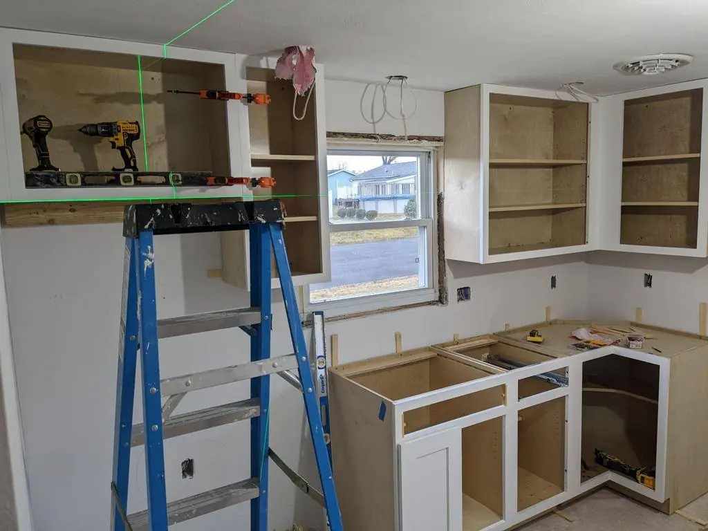 Wall cabinets being hung to a laser level line during installation