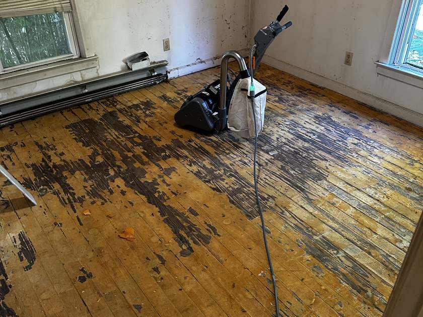 Original hardwood floor covered in decades of black carpet adhesive with a floor sander, sanded to satisfy the lender before settlement