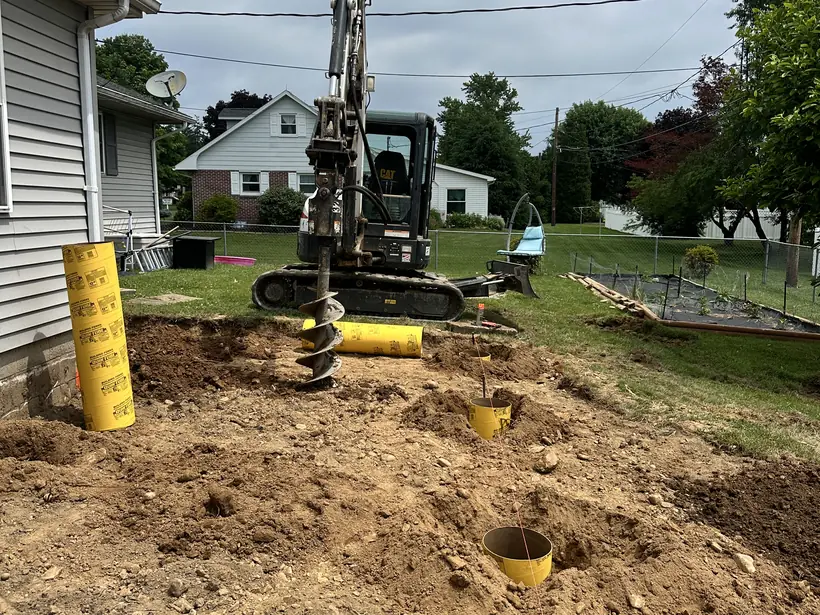 Auger drilling deck footings below frost depth with a form tube set in the hole