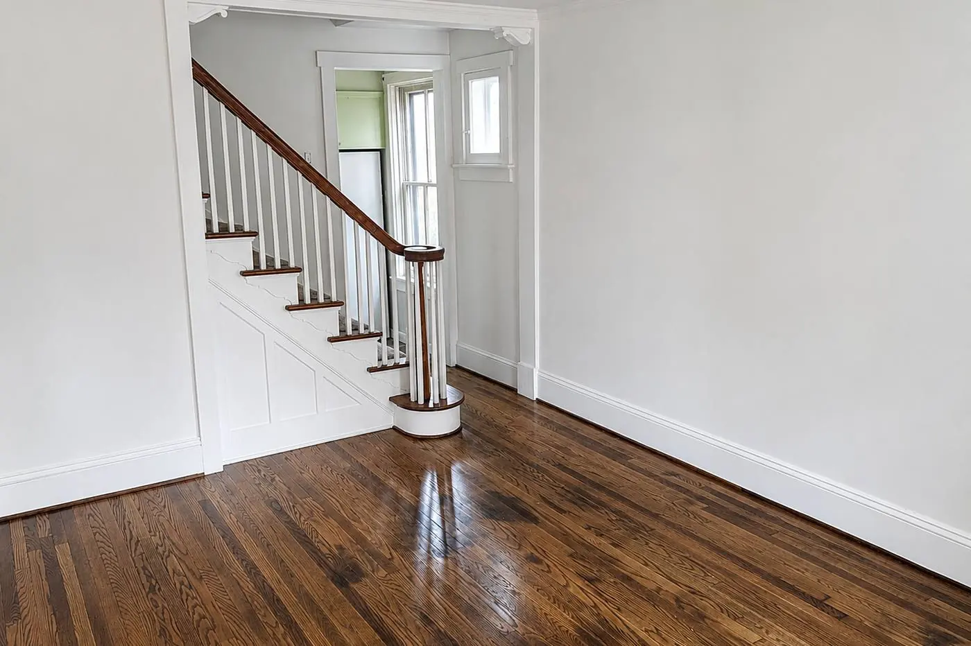 Refinished oak floors and an original staircase with a turned newel post in a whole-home renovation by Smego Construction in Central Pennsylvania