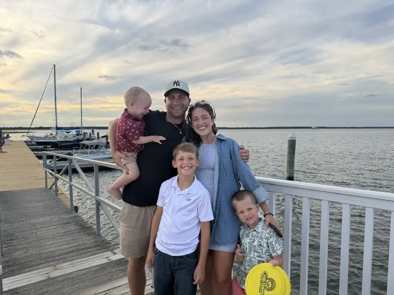 Mike Smego with his wife and their three sons on a dock at sunset