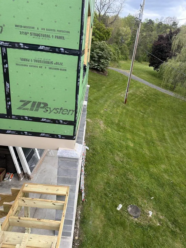 Sheathing detail at the corner of the addition, with the overhead service lines visible beyond