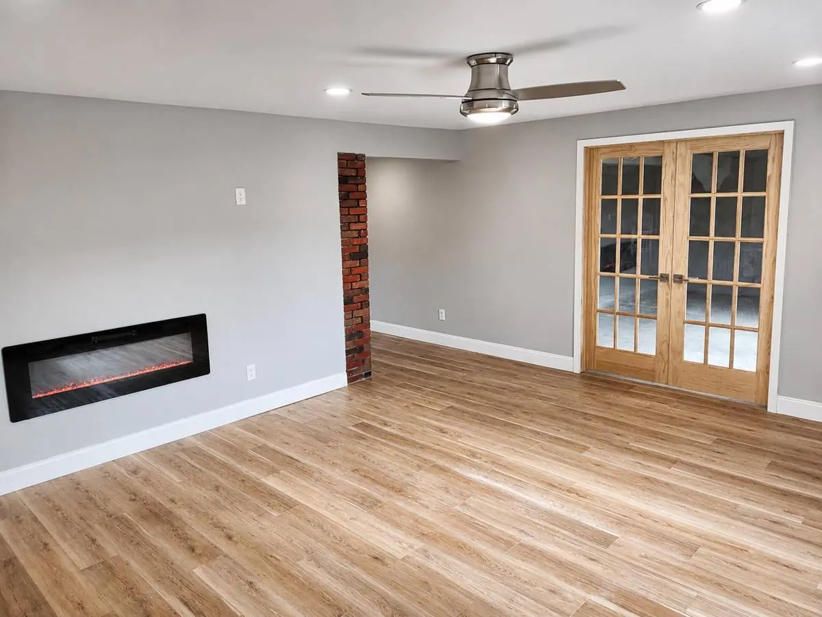 Finished basement master bedroom in Northumberland, Pennsylvania, with luxury vinyl plank flooring, a linear electric fireplace and an exposed brick chimney