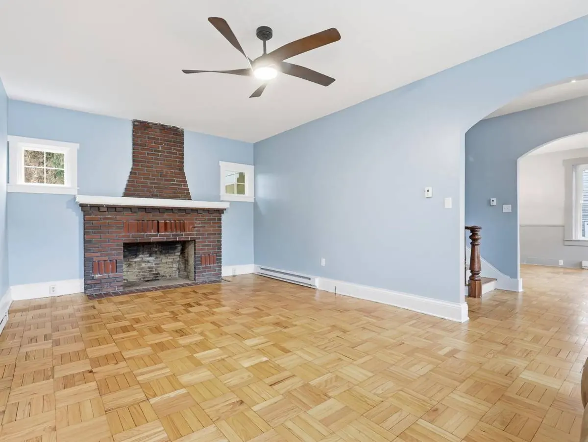 Restored living room with original brick fireplace, parquet floor and period trim