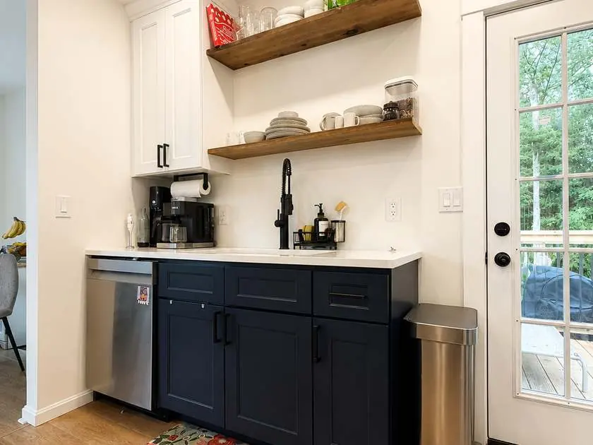 Finished kitchen with navy cabinets, quartz counters and floating wood shelves