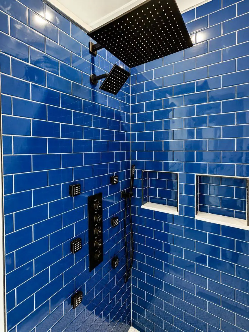 Cobalt blue subway tiled shower with a rainfall head, second overhead, six body jets, hand shower and thermostatic valve
