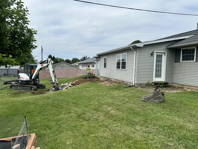 Backyard in Shamokin Dam before the deck, with an excavator arriving to begin footings