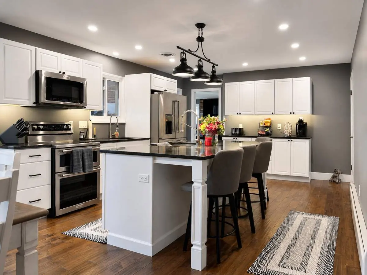 Finished Danville kitchen with white shaker cabinets, stainless appliances, under-cabinet lighting and a granite-topped island with bar seating