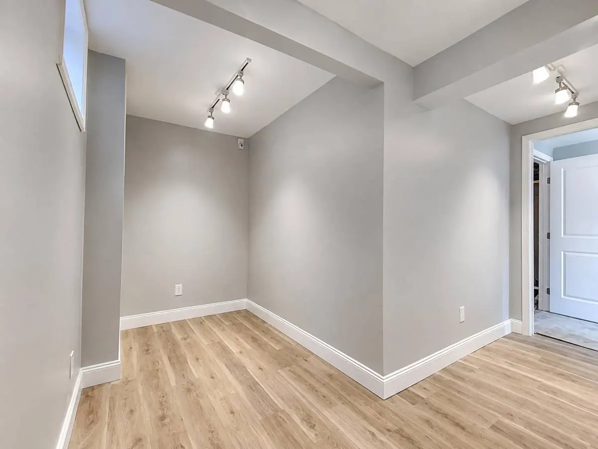 Finished walk-in closet in a basement master suite with track lighting and luxury vinyl plank flooring