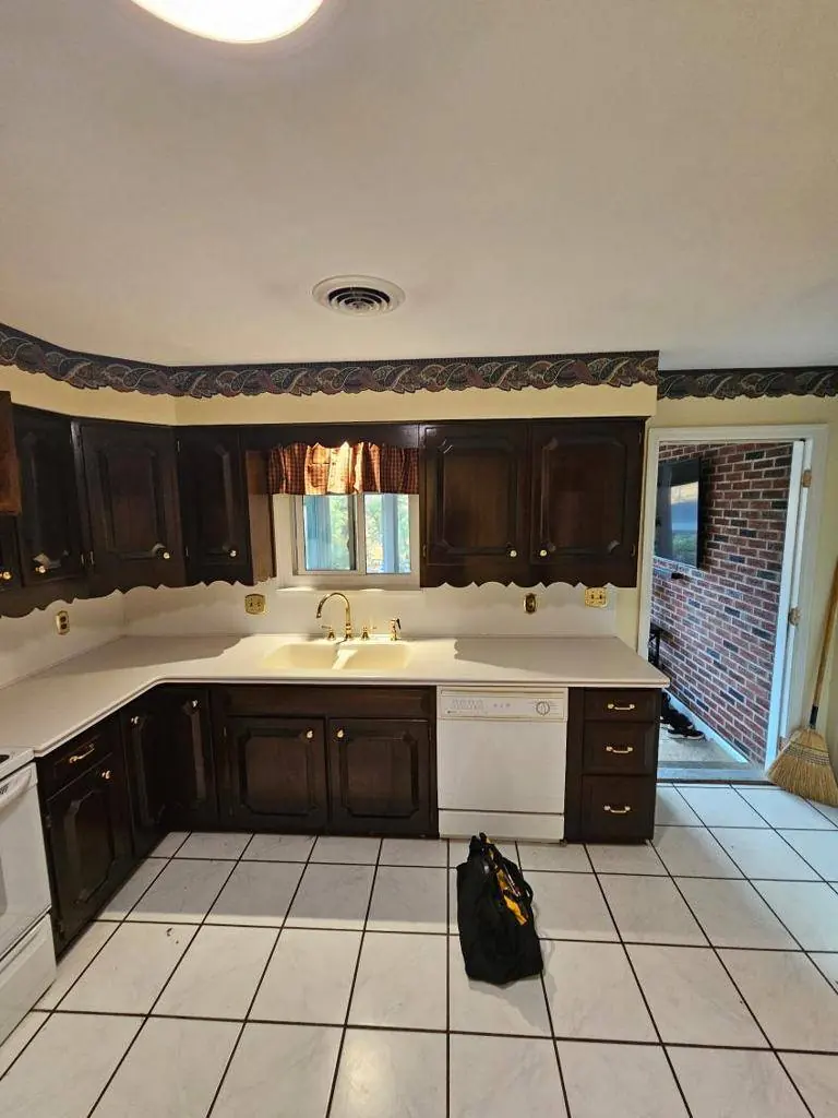 Danville kitchen before remodeling, with dark oak cabinets, white tile flooring, a wallpaper border and a closed-off layout