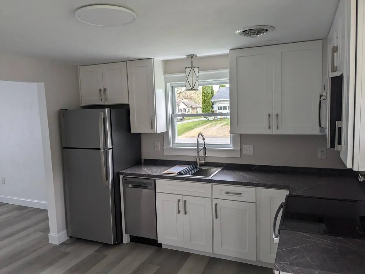 Finished Selinsgrove kitchen with white shaker cabinets, stainless refrigerator and dishwasher, and a window over the sink