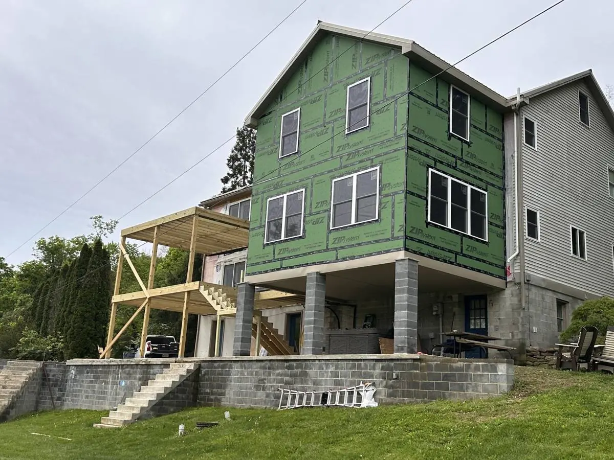 The addition dried in and windows installed, seen from the yard below the retaining wall