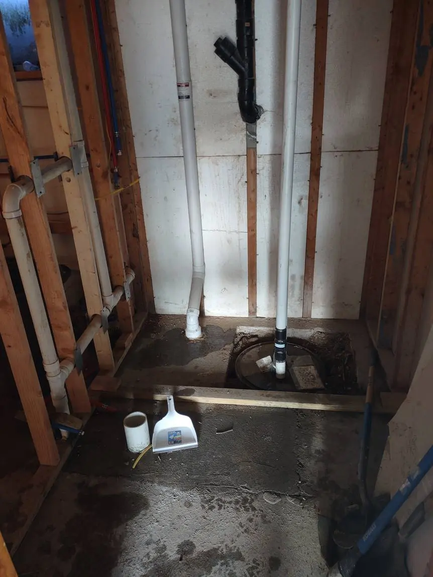 New PVC drain lines and PEX water lines roughed in inside the open trench before the basement floor was poured back