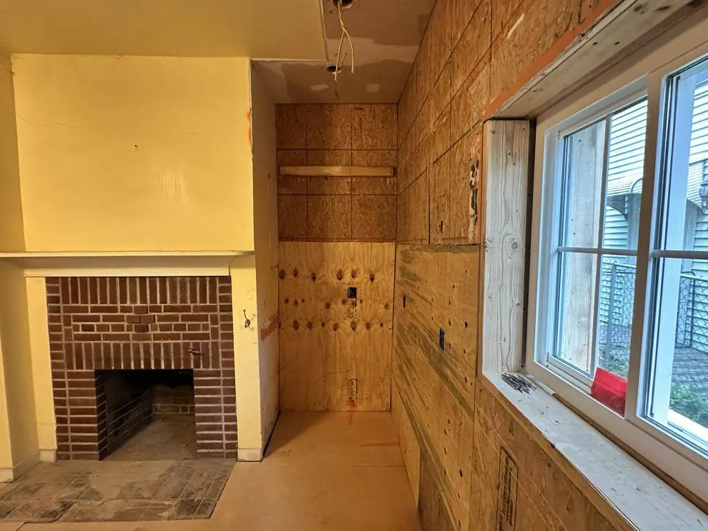 Room stripped back to original plank sheathing and brick, with the fireplace exposed