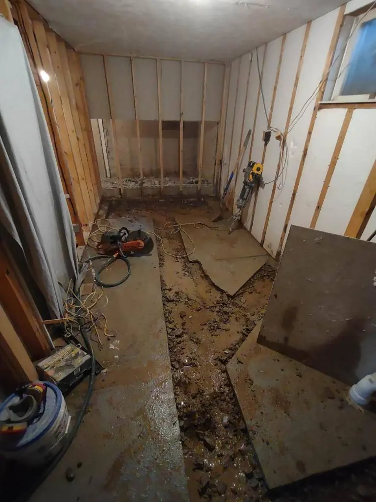 Concrete slab saw-cut and broken out to run new bathroom drain lines under a basement floor