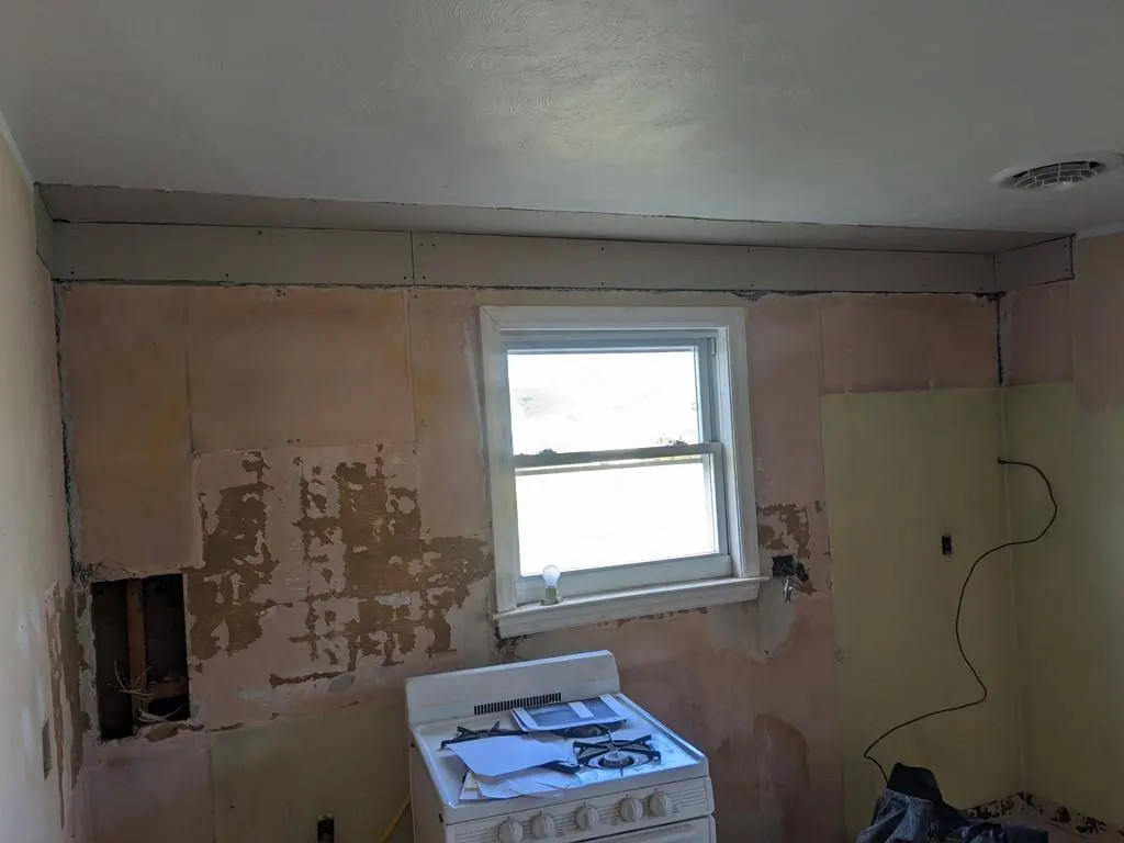 Selinsgrove kitchen stripped back to bare plaster and framing before the remodel, with the original gas range still in place