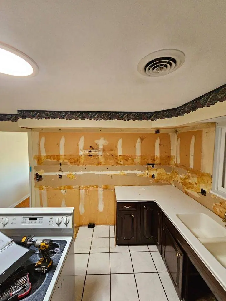 Original kitchen before demolition showing dark cabinets, laminate countertops and the soffit running above the wall cabinets