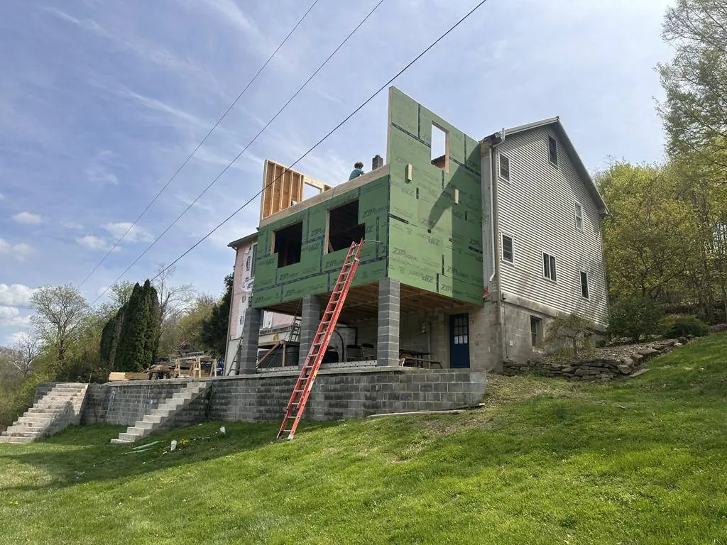Addition framed and sheathed, showing the full height from the walk-out basement to the new roof