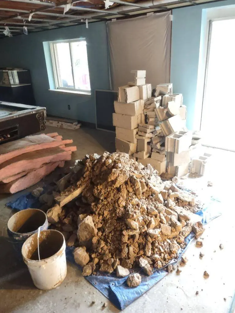 Concrete and soil excavated by hand from the basement slab trench and stacked for removal by bucket