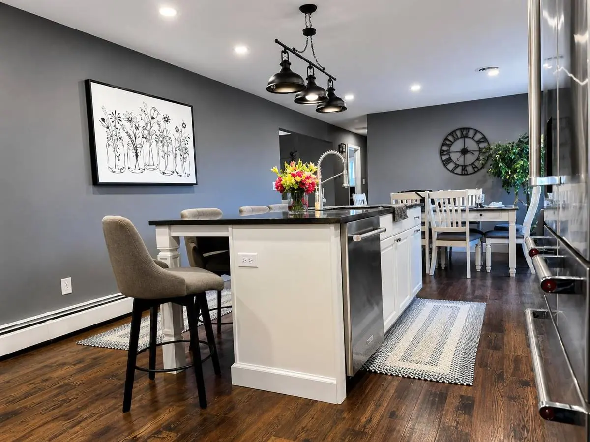 Kitchen island with bar seating opening into the dining area, with pendant lighting and hardwood flooring