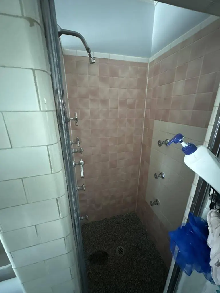 The original tiled shower before demolition, with salmon tile and six vintage chrome wall valves