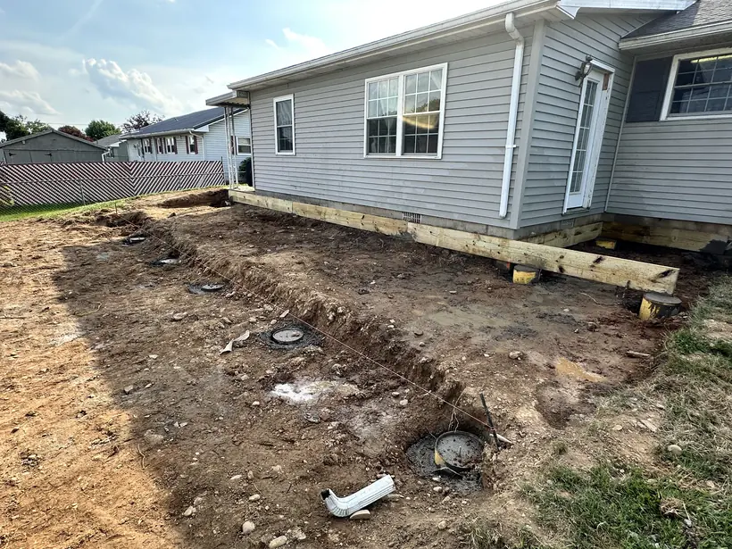 Concrete footings poured and form tubes set in the graded yard before framing